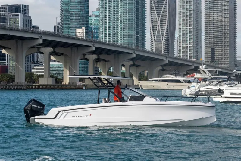 Slide: The Image of 2024 Axopar 25 Cross Top boat cruising near a city bridge with skyscrapers in the background. - 4