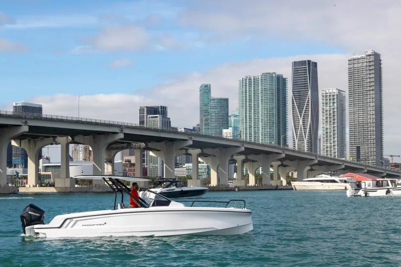The Image of 2024 Axopar 25 Cross Top boat cruising near a city bridge with skyscrapers in the background. - 0