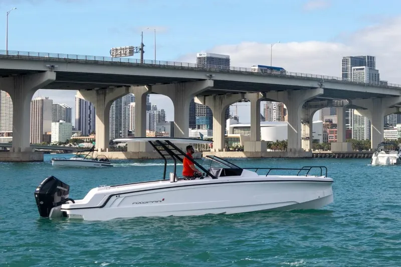 Slide: The Image of 2024 Axopar 25 Cross Top boat cruising under a city bridge. - 3