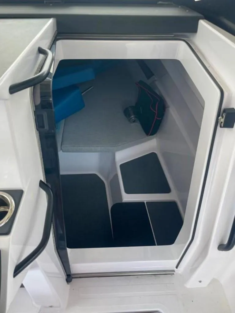 Slide: The Image of 2024 Axopar 25 Cross Top cabin interior with seating and storage. - 12