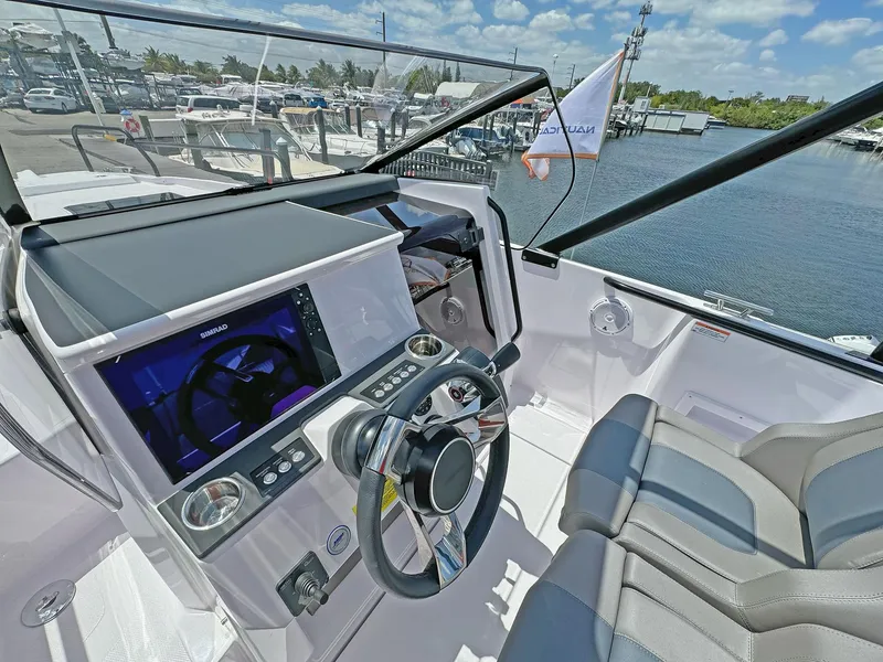 Slide: The Image of 2024 Axopar 25 Cross Top boat cockpit with modern controls and waterfront view. - 6