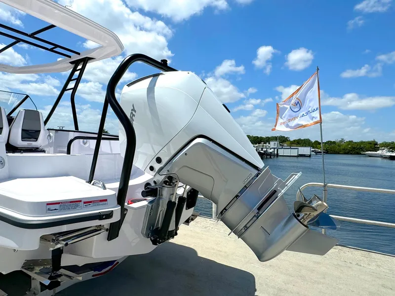 Slide: The Image of 2024 Axopar 25 Cross Top boat with powerful outboard motor docked by the water. - 2
