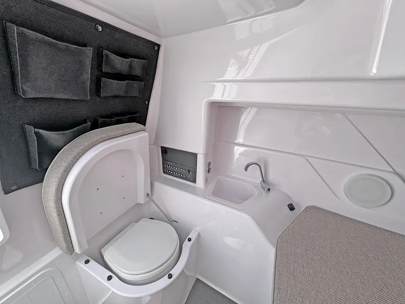 Slide: The Image of 2024 Axopar 25 Cross Top interior with toilet, sink, and storage compartments. - 8