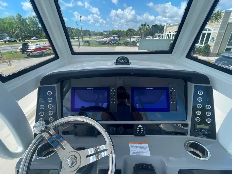 Slide: The Image of 2023 Robalo R270 boat dashboard with dual Simrad displays and steering wheel. - 16