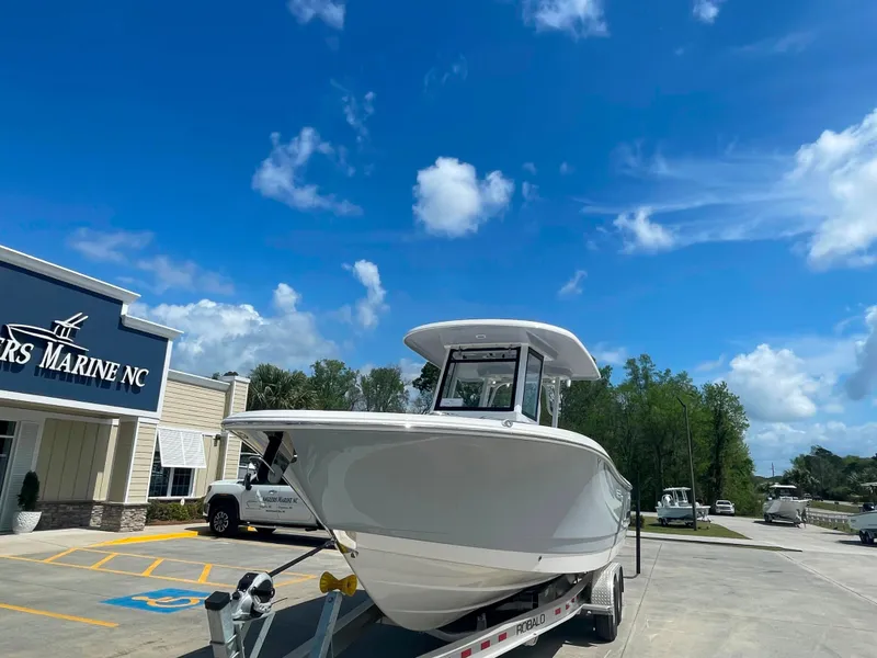 Slide: The Image of 2023 Robalo R270 boat on trailer at dealership under blue sky. - 5