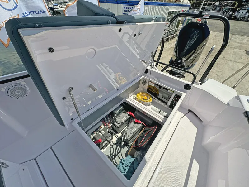 Slide: The Image of 2025 Axopar 25 Cross Top boat storage compartment with open lid, showcasing internal equipment. - 7