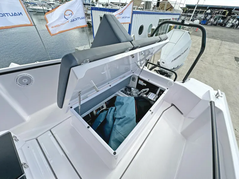 Slide: The Image of 2025 Axopar 25 Cross Top boat storage compartment open at marina. - 15