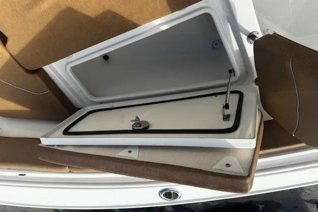 Slide: The Image of 2023 Sea Hunt Ultra 255 SE storage compartment with open hatch and cushioned seating. - 13