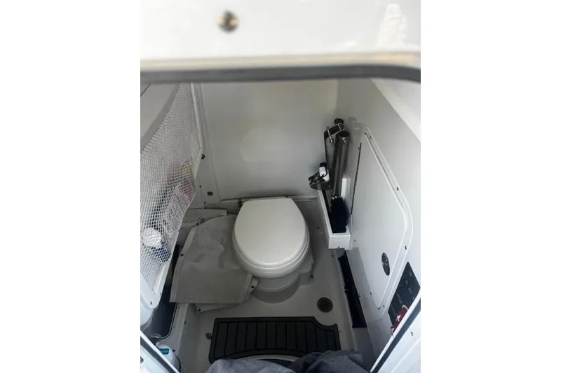 Slide: The Image of 2023 Sea Hunt Ultra 255 SE boat interior bathroom with toilet and storage. - 6
