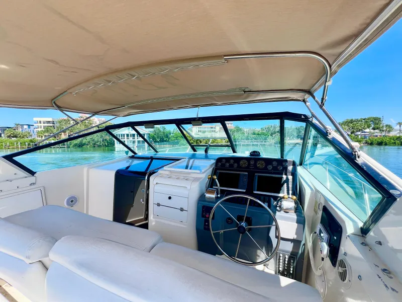 Slide: The Image of 1998 Tiara Yachts 3500 Express cockpit with steering wheel, dashboard, and waterfront view. - 12