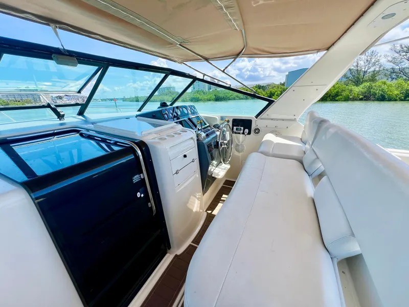 Slide: The Image of 1998 Tiara Yachts 3500 Express cockpit with white seating and helm, overlooking serene waters. - 13