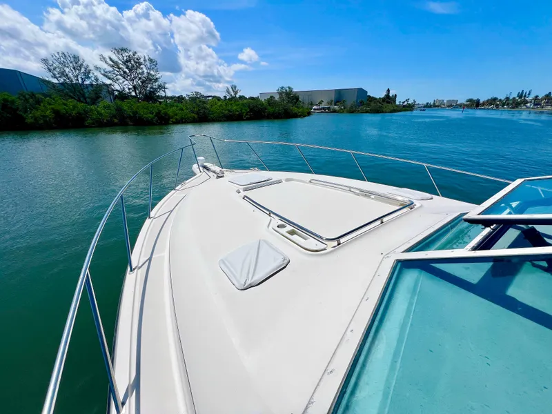 Slide: The Image of 1998 Tiara Yachts 3500 Express cruising on a serene river under a clear blue sky. - 16