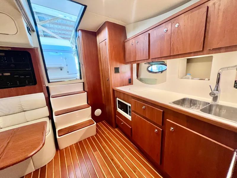 Slide: The Image of Luxurious 1998 Tiara Yachts 3500 Express interior with wooden cabinetry and modern kitchen amenities. - 18