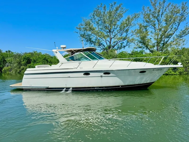 Slide: The Image of 1998 Tiara Yachts 3500 Express cruising on a sunny day, surrounded by lush greenery. - 2