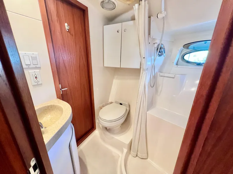 Slide: The Image of 1998 Tiara Yachts 3500 Express bathroom with shower, sink, and wooden door. - 24