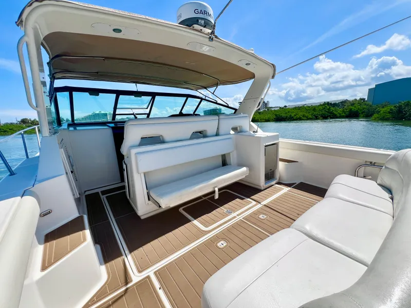 Slide: The Image of 1998 Tiara Yachts 3500 Express boat interior with seating, docked on a sunny day. - 9