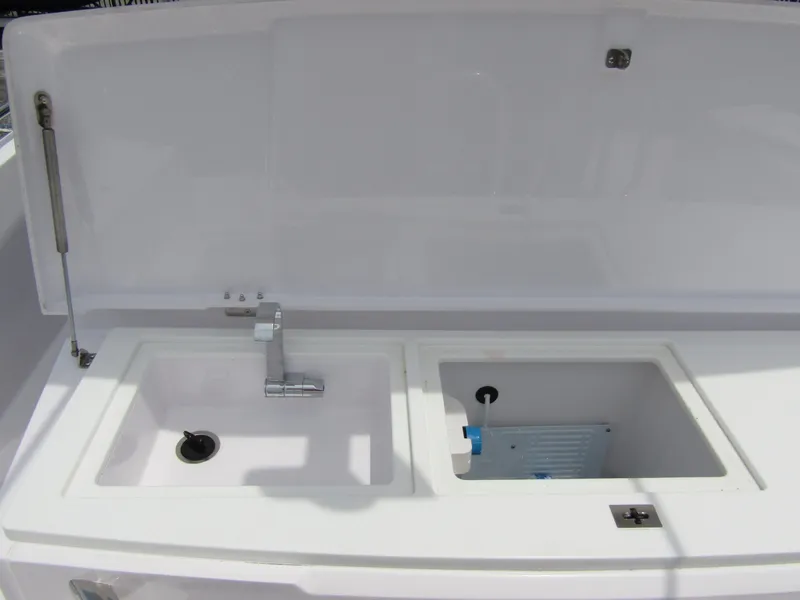 Slide: The Image of 2024 Axopar 37 Sun Top boat sink and storage area with open lid. - 32