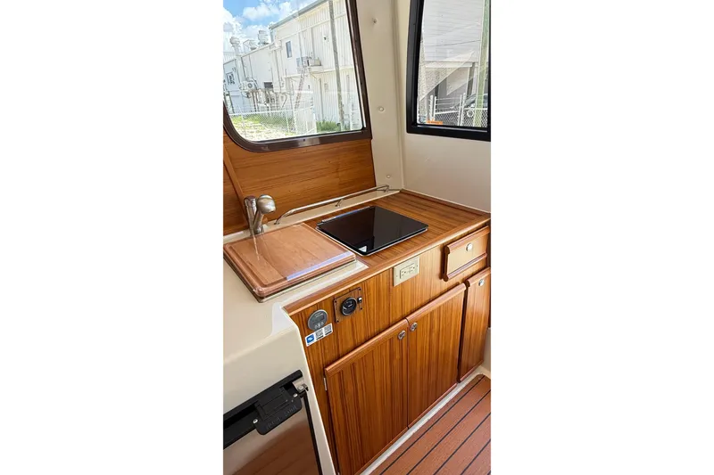 Slide: The Image of 2025 Ranger Tugs R-23 interior with wooden cabinetry and compact kitchen area. - 4
