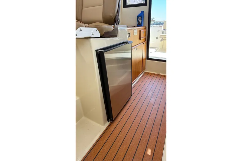 Slide: The Image of 2025 Ranger Tugs R-23 interior with compact fridge and wooden flooring. - 6