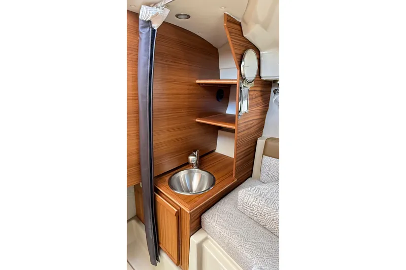 Slide: The Image of 2025 Ranger Tugs R-23 interior with wooden shelves and compact sink. - 7