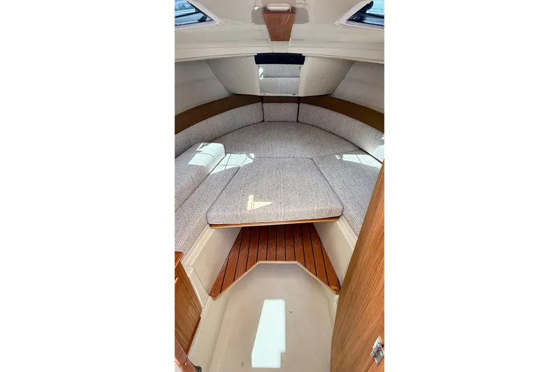 Slide: The Image of 2025 Ranger Tugs R-23 cabin interior with cushioned seating and wooden accents. - 9