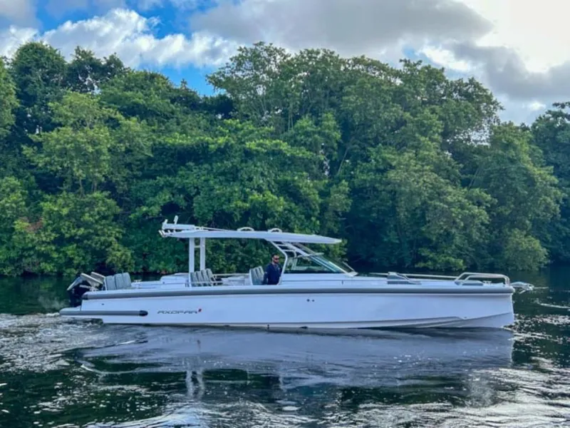 The Image of 2024 Axopar 37 Sun Top boat cruising on a river with lush green trees in the background. - 0