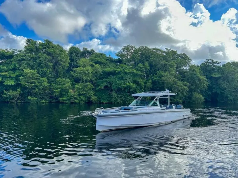 Slide: The Image of 2024 Axopar 37 Sun Top boat cruising on a serene lake with lush greenery. - 1