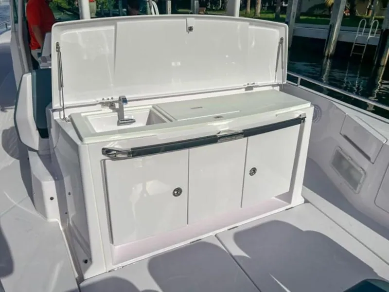 Slide: The Image of 2024 Axopar 37 Sun Top boat interior with open storage compartment and sink. - 20