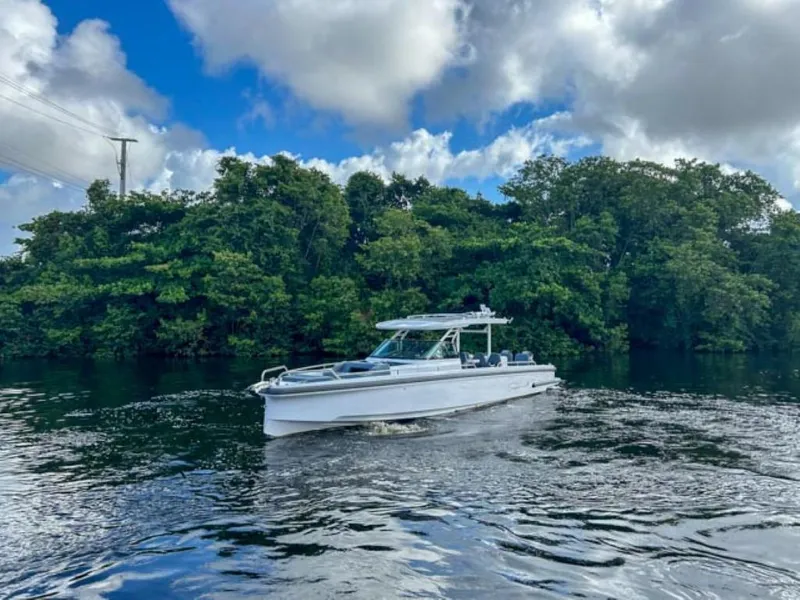 Slide: The Image of 2024 Axopar 37 Sun Top boat cruising on a river with lush green trees in the background. - 4