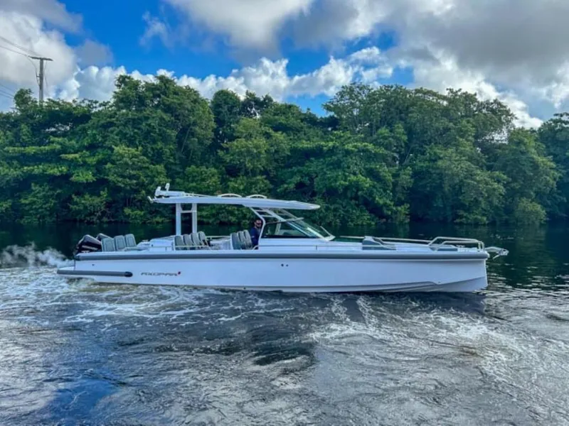 Slide: The Image of 2024 Axopar 37 Sun Top cruising on a river with lush green trees in the background. - 6