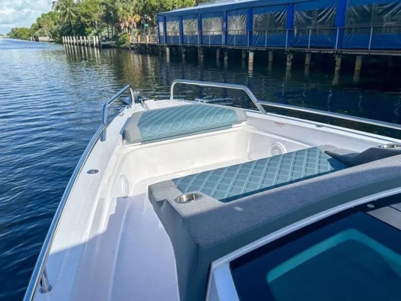 Slide: The Image of 2024 Axopar 37 Sun Top boat with cushioned seating on a calm waterway. - 8