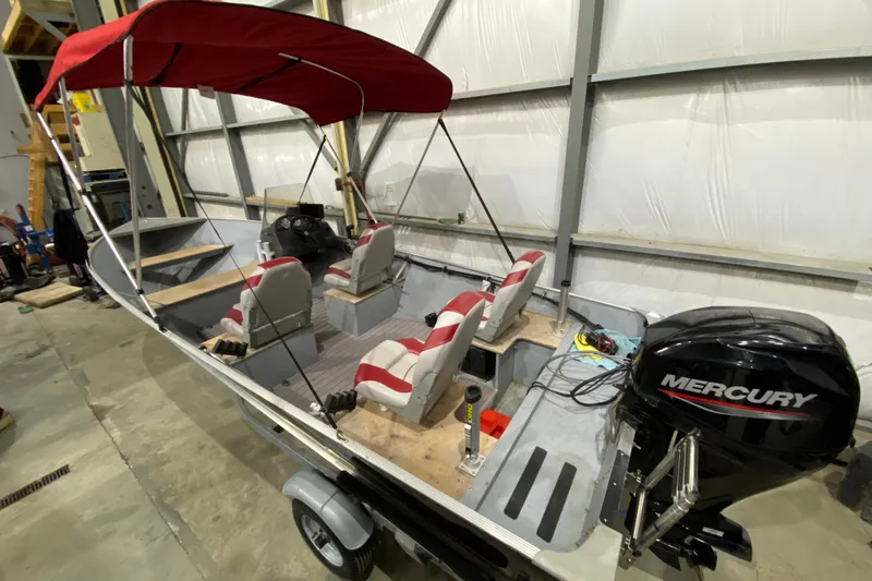 Slide: The Image of 2021 Lund SSV-18 boat with red canopy and Mercury outboard motor in a garage. - 6