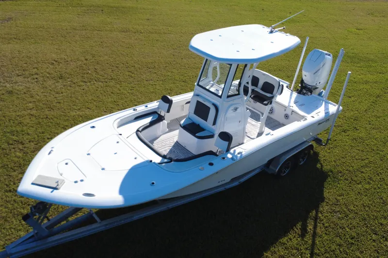 Slide: The Image of 2024 Tidewater 2500 Carolina Bay boat on trailer, parked on grass with palm trees in background. - 10