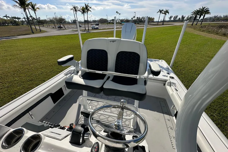 Slide: The Image of 2024 Tidewater 2500 Carolina Bay boat interior with steering wheel and seating, parked on grass. - 40