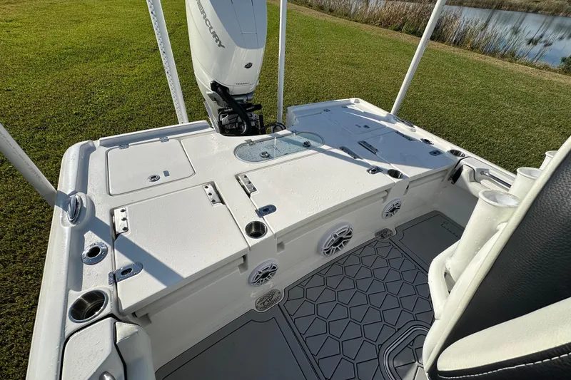 Slide: The Image of 2024 Tidewater 2500 Carolina Bay boat deck with Mercury engine, featuring storage and speakers. - 43