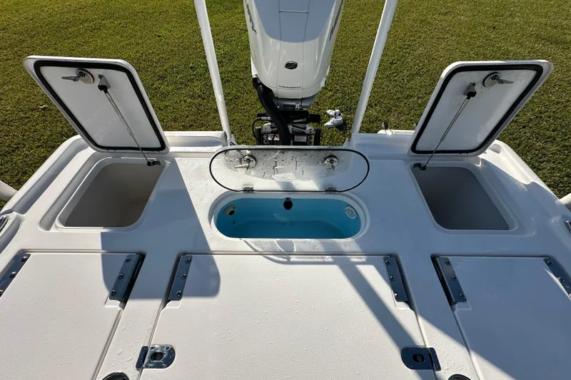 Slide: The Image of 2024 Tidewater 2500 Carolina Bay boat deck with open storage compartments and motor. - 46
