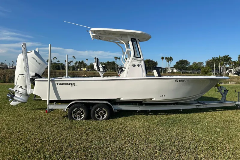 Slide: The Image of 2024 Tidewater 2500 Carolina Bay boat on trailer, parked on grass under clear blue sky. - 6