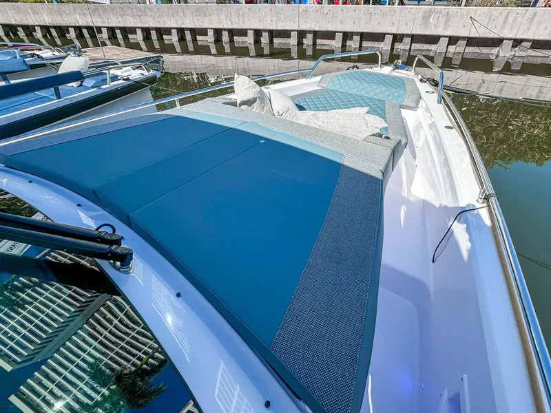Slide: The Image of 2024 Axopar 37 Sun Top boat with sleek blue sunbathing deck by the water. - 31
