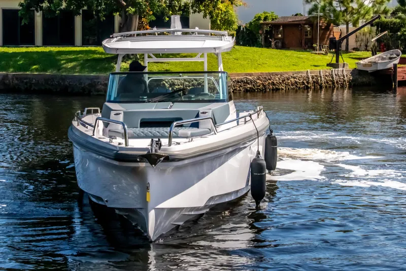 Slide: The Image of 2024 Axopar 37 Sun Top cruising on a calm river, surrounded by greenery. - 4