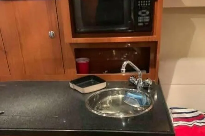 Slide: The Image of 2006 Regal 3060 Window Express yacht kitchen with sink, microwave, and wooden cabinetry. - 12