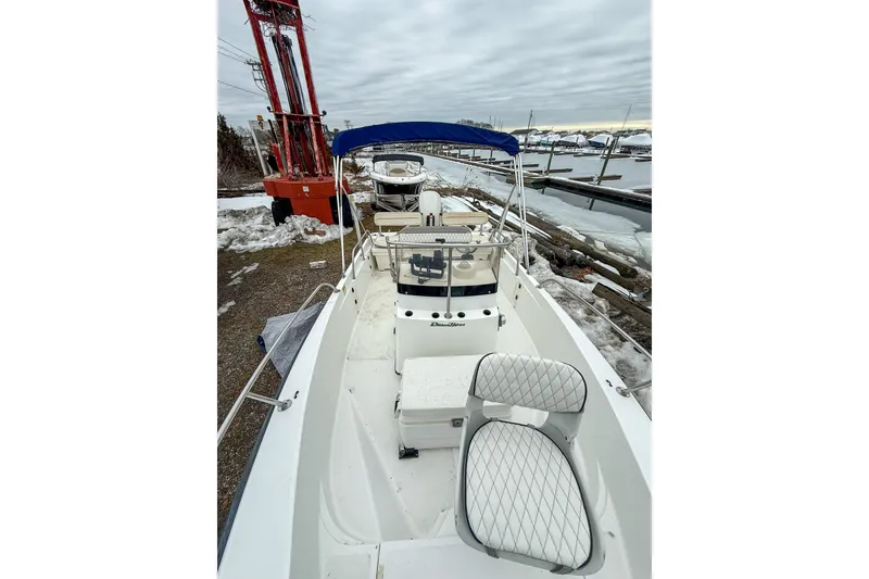 Slide: The Image of 1999 Boston Whaler 18 Dauntless boat with blue canopy, docked in snowy marina. - 11