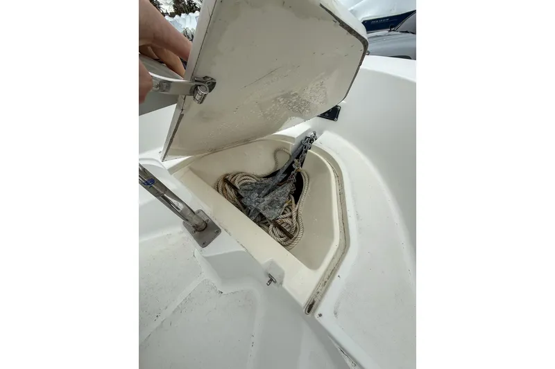 Slide: The Image of Open storage compartment on 1999 Boston Whaler 18 Dauntless boat, showing ropes and anchor. - 18
