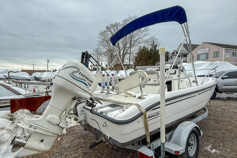 Slide: The Image of 1999 Boston Whaler 18 Dauntless boat with Evinrude motor on trailer, parked outdoors. - 3