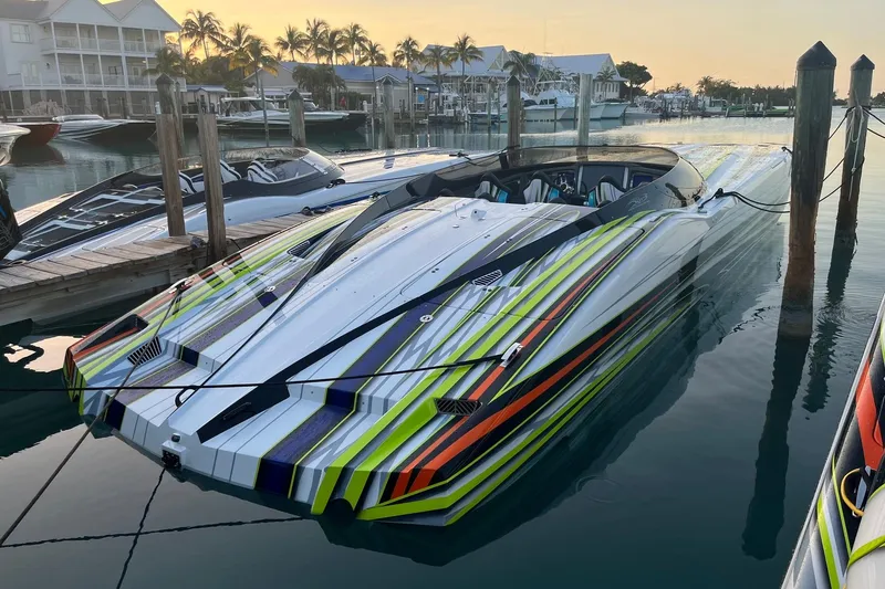 The Image of 2022 MTI 48 speedboat with vibrant stripes docked at a marina during sunset. - 1