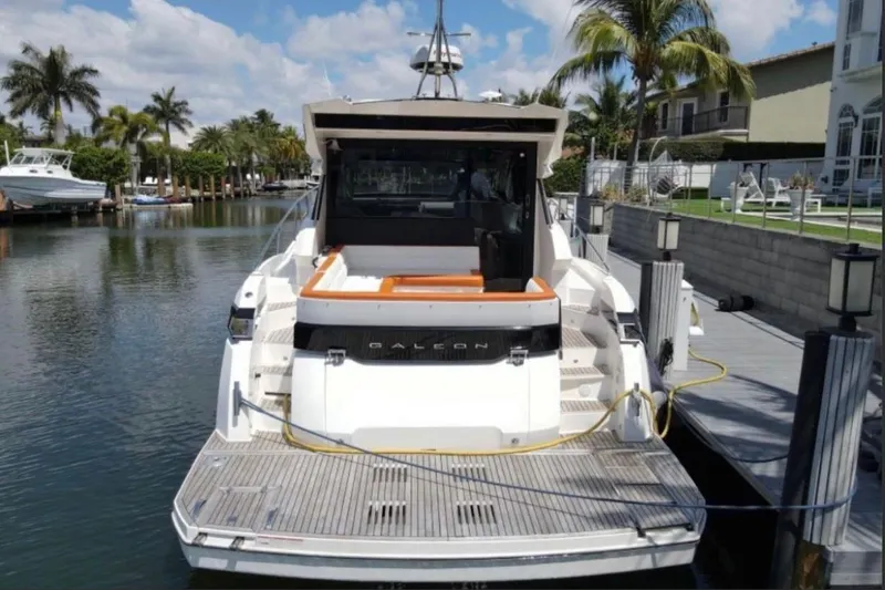 Slide: The Image of 2017 Galeon 445 HTS yacht docked by palm trees and waterfront homes. - 30