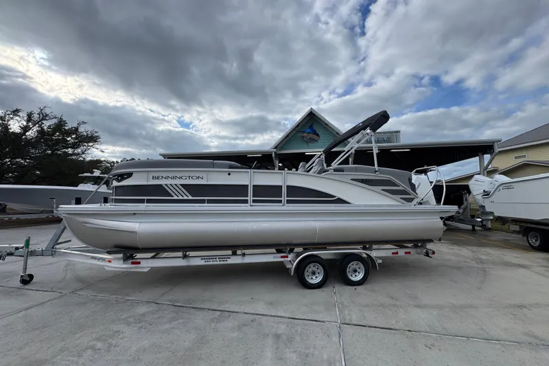 The Image of 2026 Bennington 24 MFB pontoon boat on trailer under cloudy sky. - 1