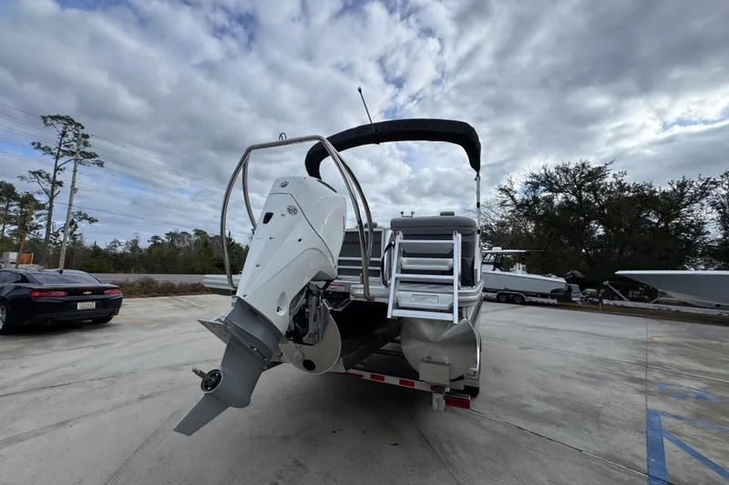 Slide: The Image of 2026 Bennington 24 MFB pontoon boat with outboard motor, parked outdoors under cloudy sky. - 12