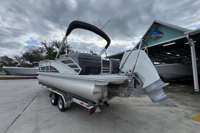 Slide: The Image of 2026 Bennington 24 MFB pontoon boat on trailer, parked outdoors under cloudy sky. - 15