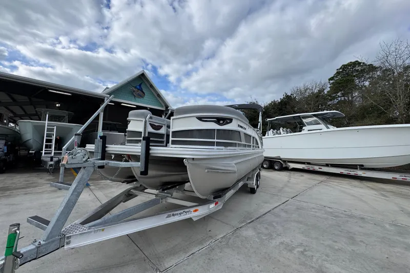 Slide: The Image of 2026 Bennington 24 MFB pontoon boat on trailer, parked outdoors under cloudy sky. - 4