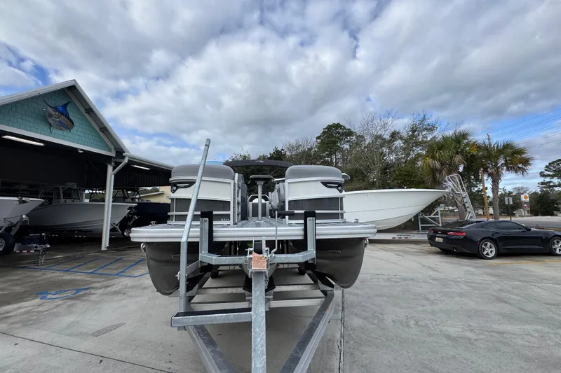 Slide: The Image of 2026 Bennington 24 MFB pontoon boat on trailer at marina with cloudy sky. - 5